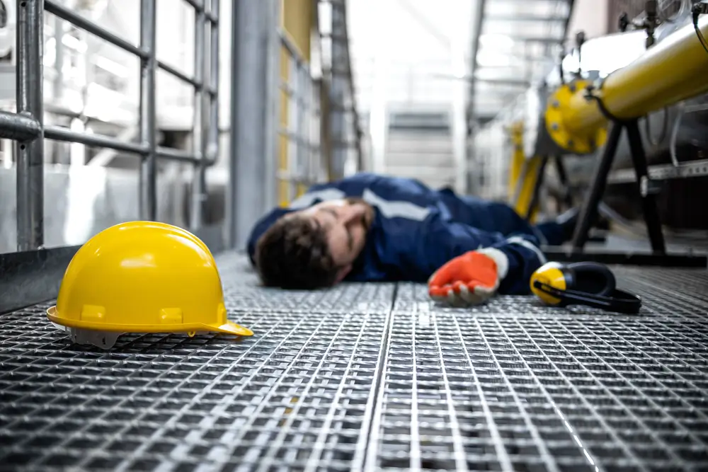 Blue collar worker lying down unconscious due to his injury at work and dizziness.