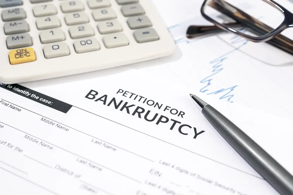 Bankruptcy form, calculator and pen on desk. Personal injury claim form