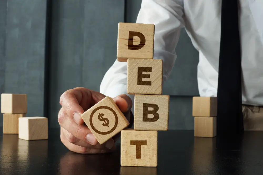 Debt is shown by wooden blocks with the word and the image of dollars. Payment of taxes and of debt to the state. Concept of financial crisis and problems. Risk management. Debt exemption and loan